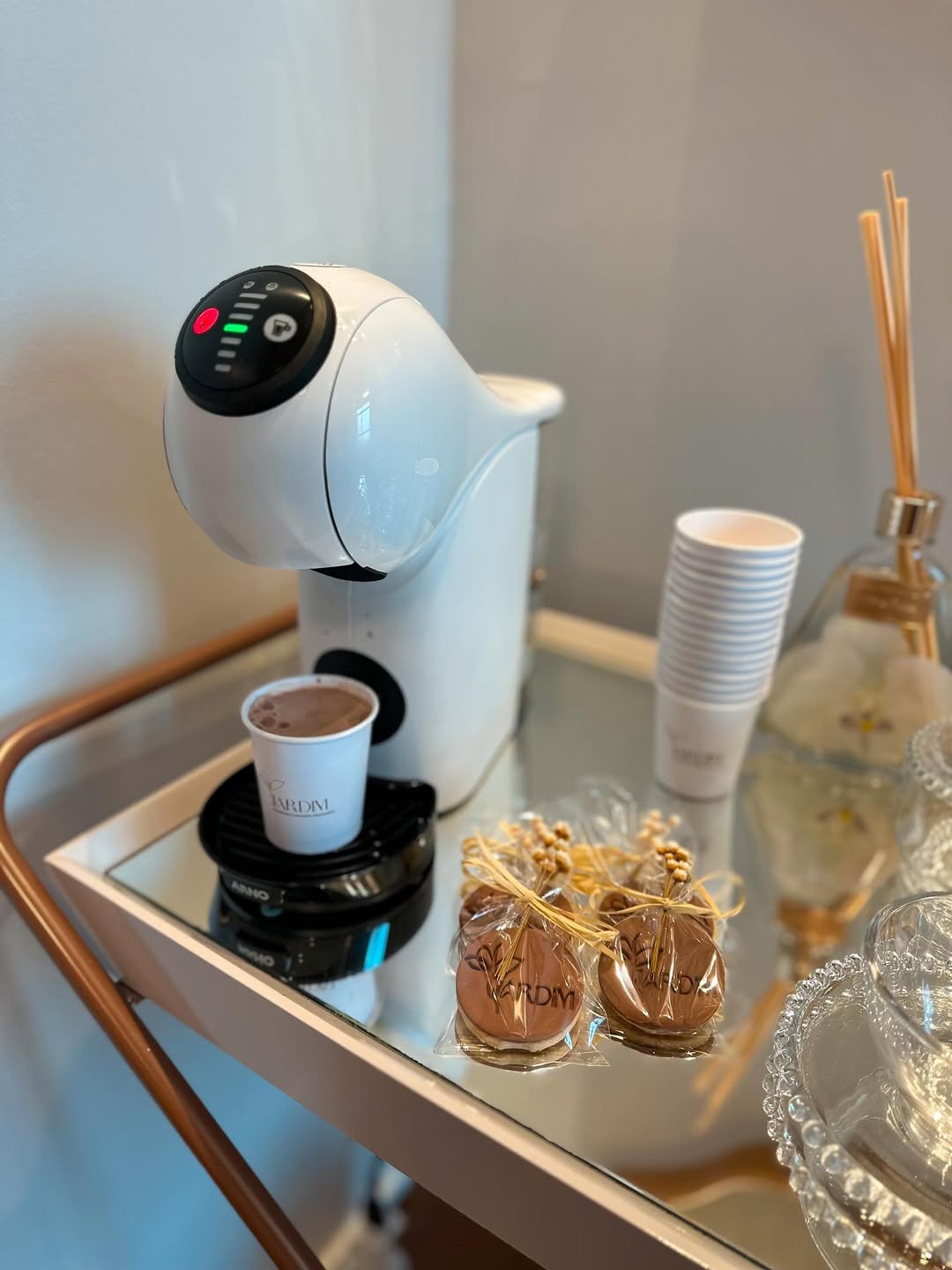 Carrinho de café da clínica, com cafeteira, xícaras e um difusor de aromas.
