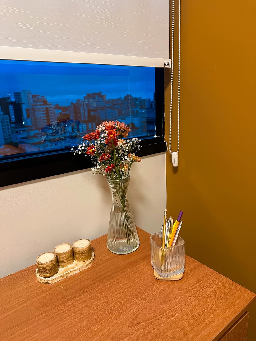 Arranjo de flores do campo sobre a mesa, com a janela ao fundo.